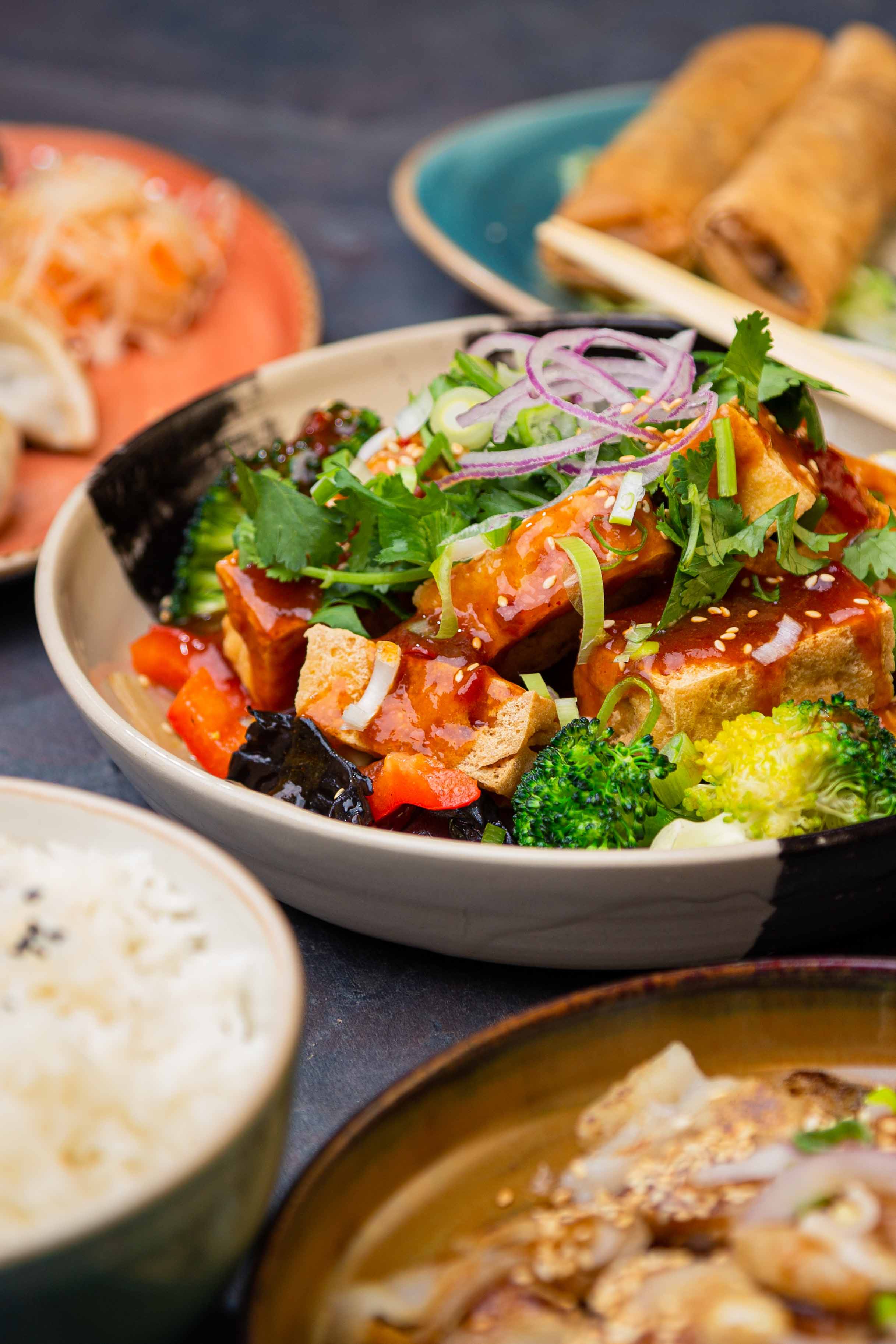 Mehrere Vorspeisen Stimmungsvoll angerichtet umkreisen eine Hauptspeise aus Tofu mit Gemüse.