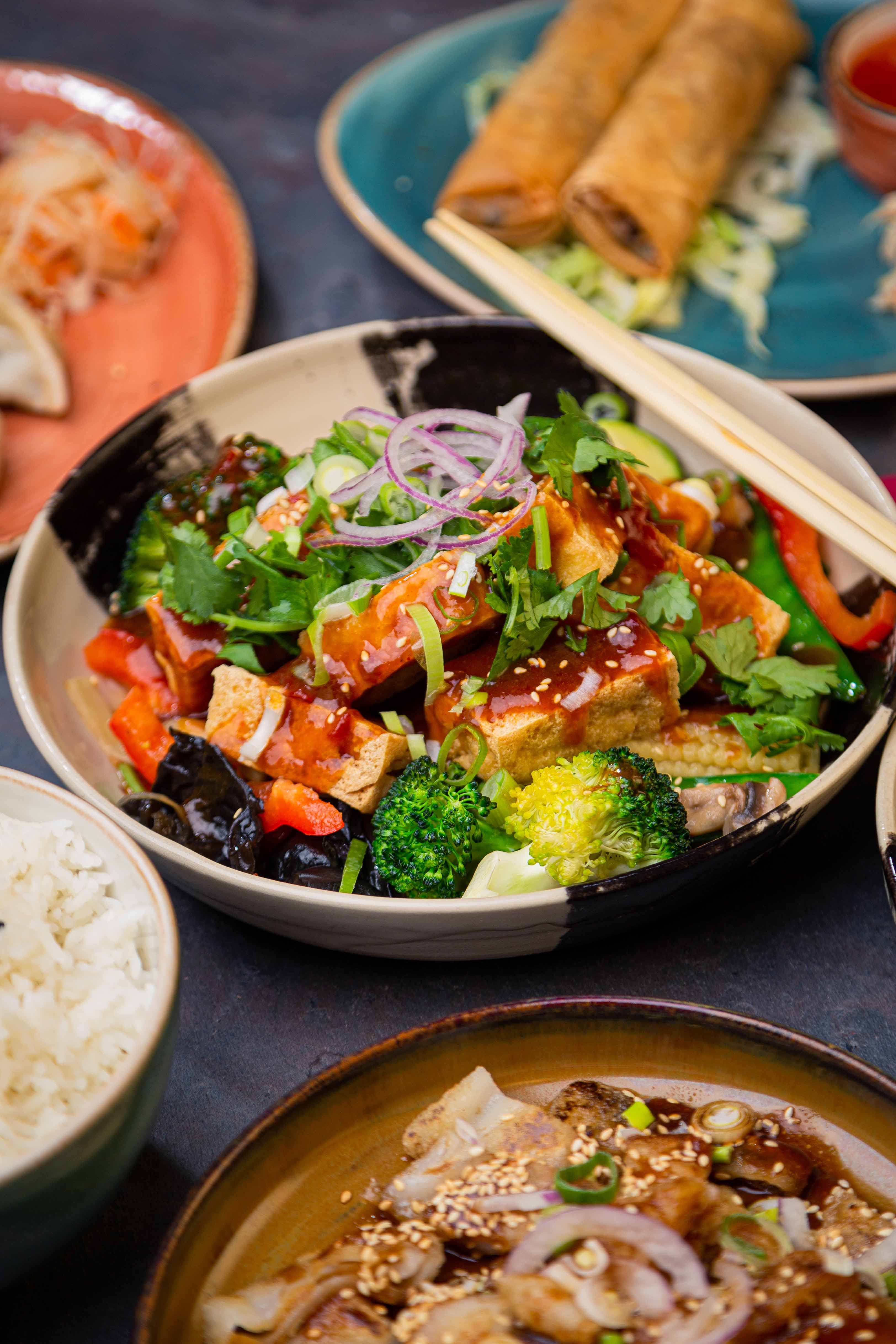 Tofu with vegetables served in a handmade plate.